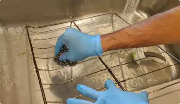 A professional cleaner wiping a dusty air vent in a modern apartment to improve indoor air quality.